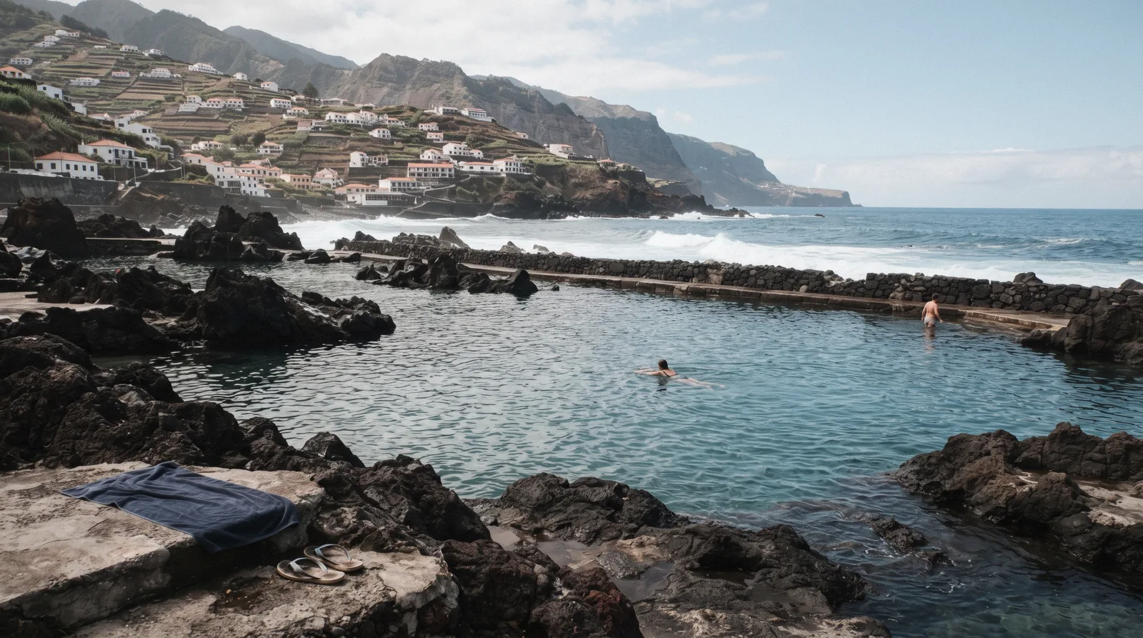 Free volcanic pools beside the Porto Moniz village shore with a few swimmers, one of the free things to do in Madeira