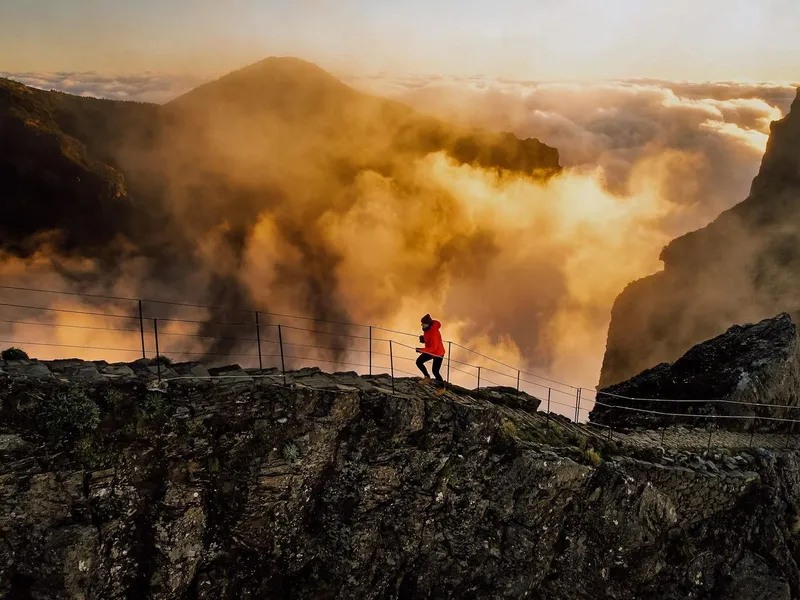 A hiker crossing a tunnel on the PR1 trail between Pico do Arieiro and Pico Ruivo on a Madeira sunrise hike transfer in Pico Ruivo, Madeira